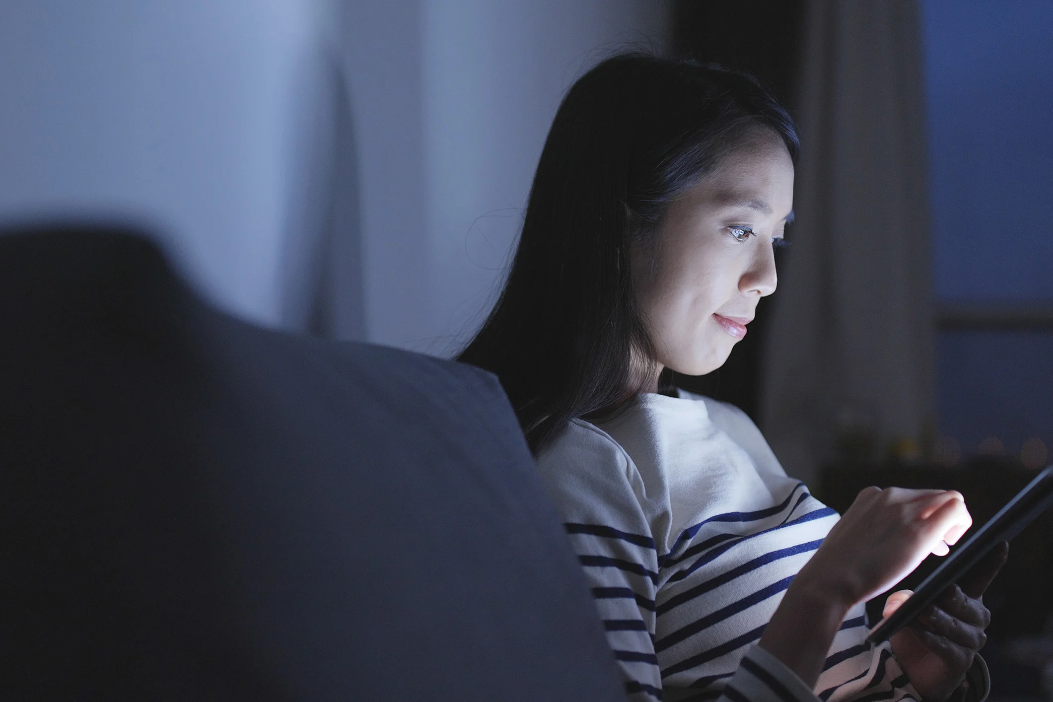 Woman in a dark room on her tablet